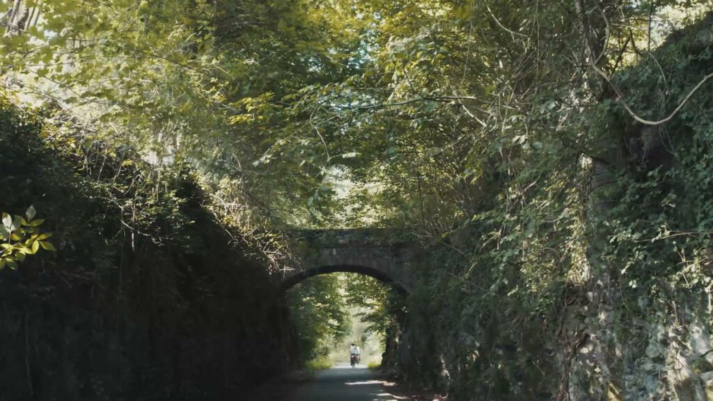 Ciclisti sotto il ponte in pietra dell’ex ferrovia, nel bosco